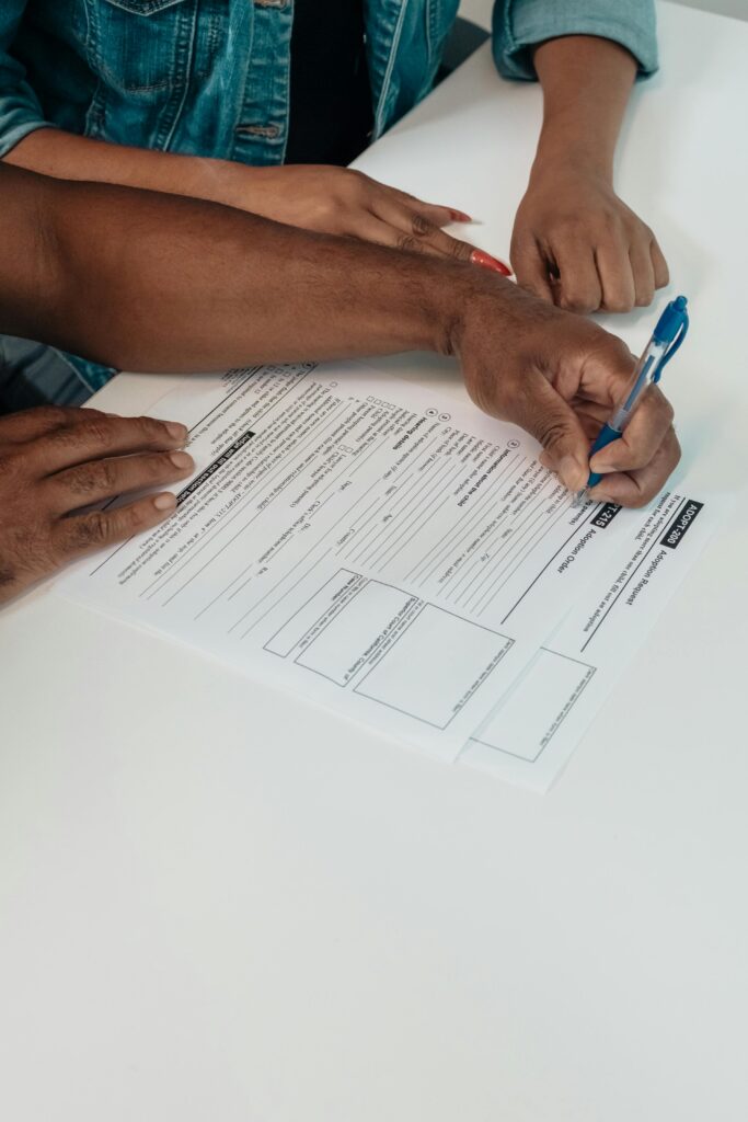 A couple signing adoption forms together at a desk in a professional setting.